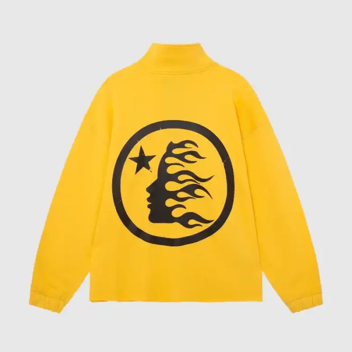 The Hellstar Studios Zipper Sweater in yellow showcases a large black circular design on the back, featuring a silhouette of a face with flame-like hair and a star against a plain gray background.